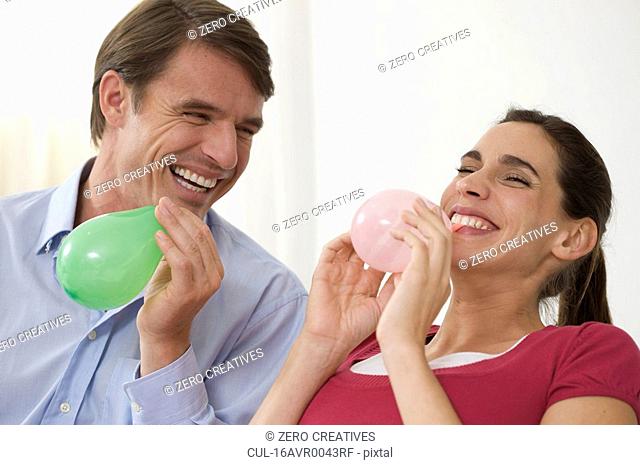 a couple having fun blowing balloons