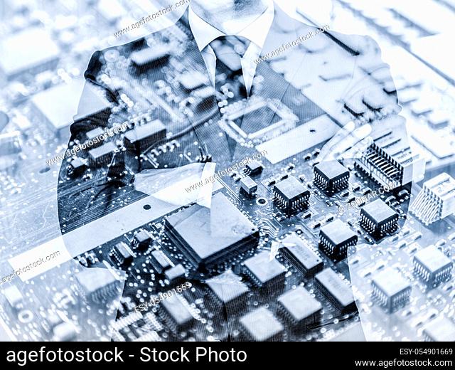 Torso of a businessman standing with folded arms in a classic navy blue suit against pc motherboard chip photo layer