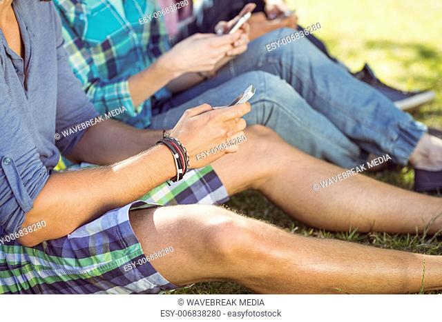 Hipsters sitting on the grass texting