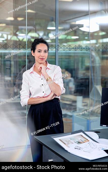 Businesswoman leaning on glass wall at office