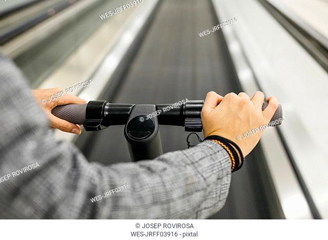 Businesswoman with her electric scooter on moving walkway