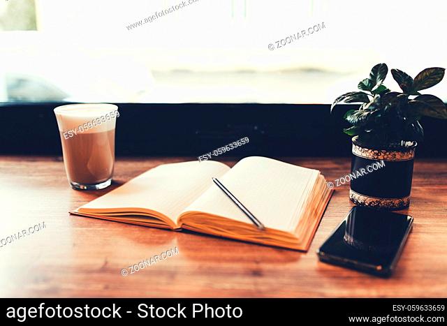 Cup of coffee, notebook, phone at table in cafe. Blurred background. High quality photo