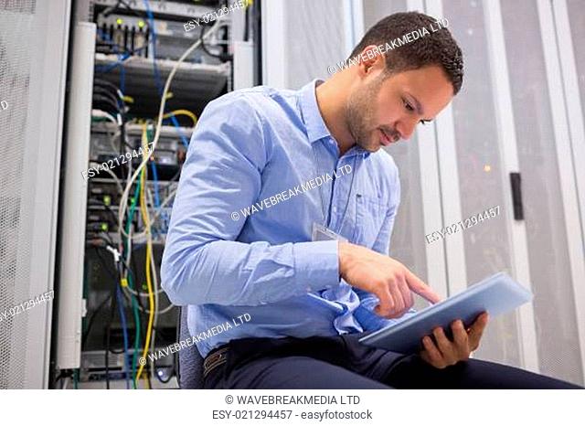 Man using tablet pc beside servers in data center