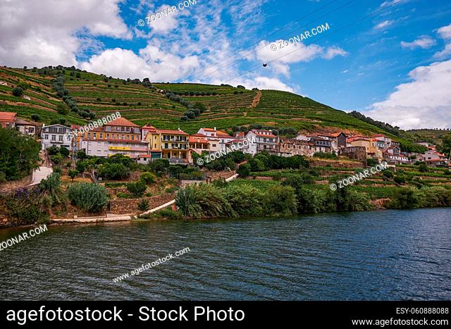 Small Village in Riverfront - View from the Cruise Boat in Douro River Valley - Port Wine Region with Farms Terraces Carved in Mountains, Portugal