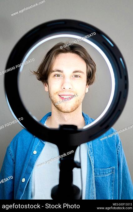 Smiling man standing in front of illuminated ring light