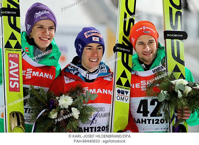 Winner Stefan Kraft (M) from Austria, Andreas Wellinger (l) from Germany and Markus Eisenbichler (r) from Germany celebrate their podium finishes at the flower...