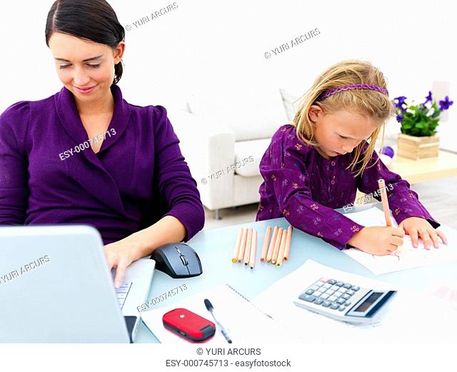 Smiling young woman using laptop with girl drawing