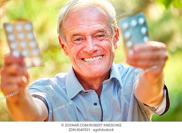 Alter Mann hält glücklich seine Medikamente in der Hand in der Natur