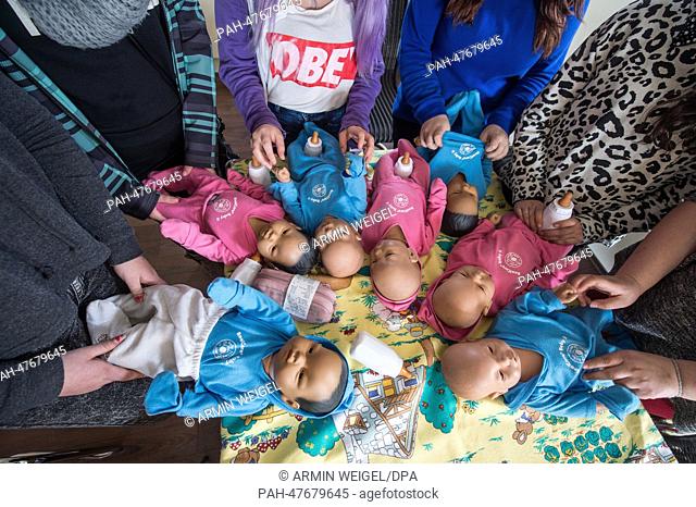 Teenage girls look after lifelike baby dolls during an internship for parents to prevent young people to get children in Amberg, Germany, 31 March 2014