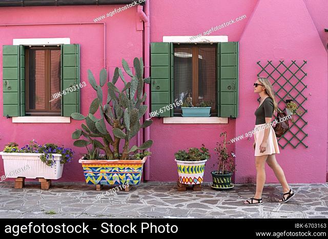 Young woman in front of colorful house, pink house facade, tourist on Burano island, Venice, Veneto, Italy, Europe