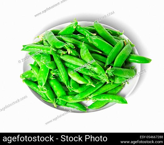 Small pile of green peas in pods on white plate isolated on white background