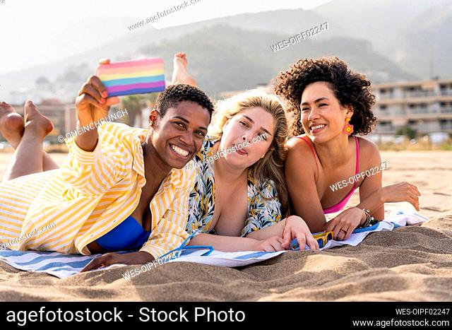 Woman making face taking selfie with friends on smart phone at beach