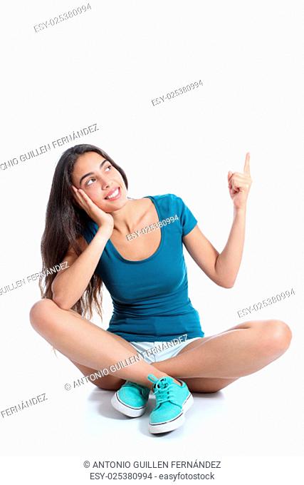Teenager girl sitting and pointing at side isolated on a white background