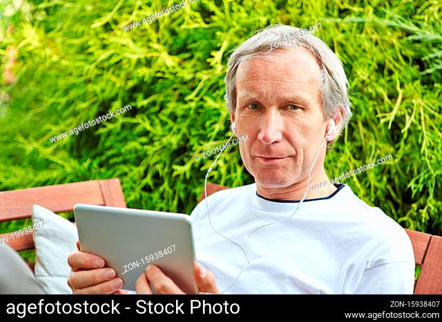 Mann mit Kopfhörer beim Online Streaming von Video auf Tablet PC