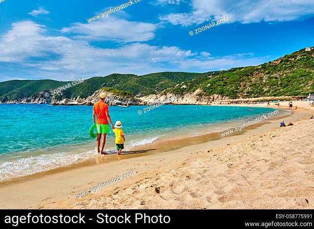 Two year old toddler boy walking on beach with father, holding inflatable ring. Summer family vacation. Sithonia, Greece