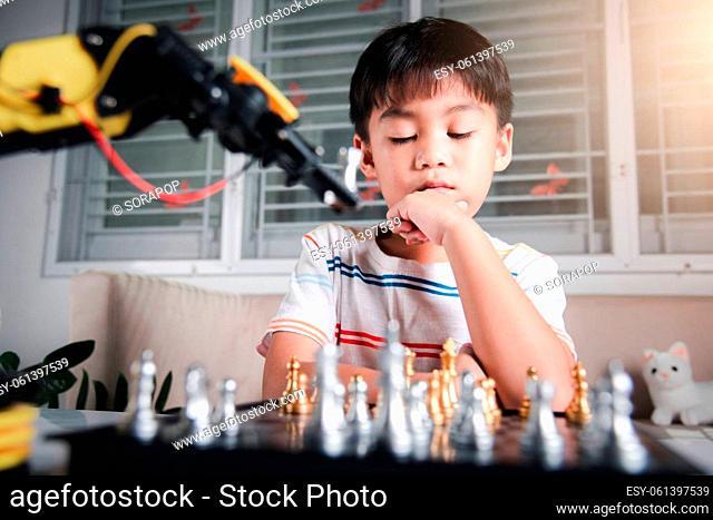 Asian little boy thinking and wait robot arm playing chess, STEM education E-learning, Funny children learning successful getting a lesson control robot arm...