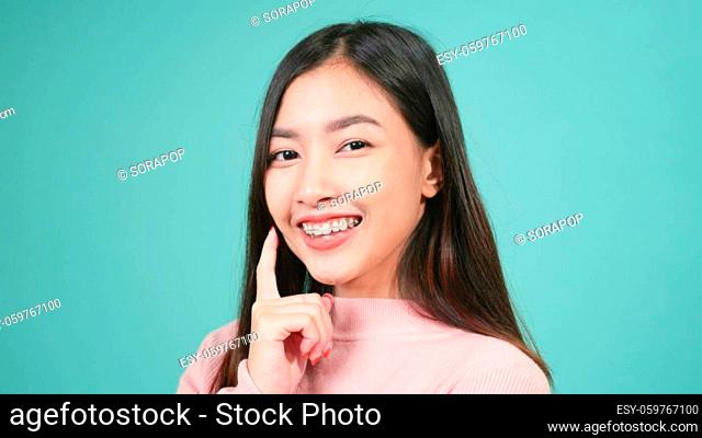Portrait young Asian beautiful woman smiling wear silicone orthodontic retainers on teeth isolated on blue background, Teeth retaining tools after removable...