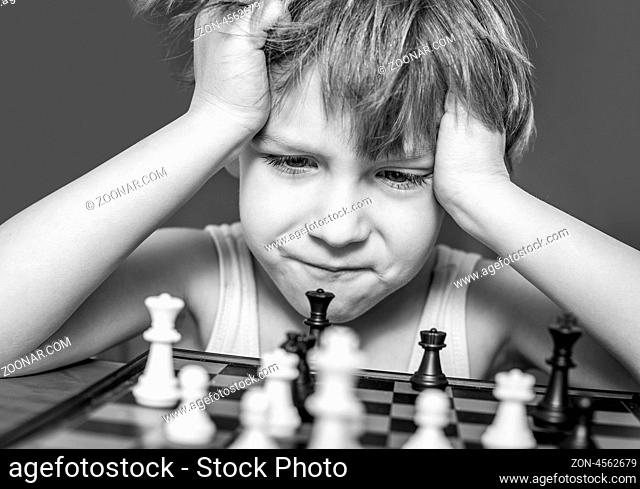 Boy playing chess, thinking how to make a move