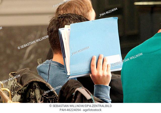 Defendant Vladan M. hides his face with a file at his trial for aggravated robbery resulting in death at the district court in Zwickau, Germany