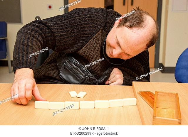 Man with disability due to road traffic accident RTA playing dominoes at a resource for people with physical and sensory impairment
