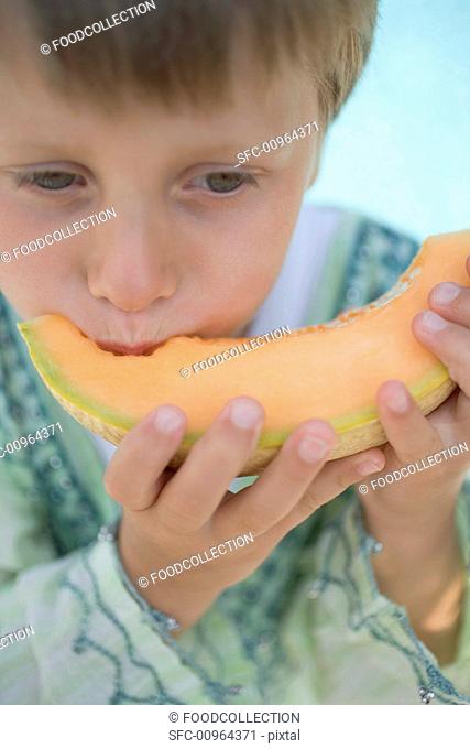 Small boy eating a slice of melon