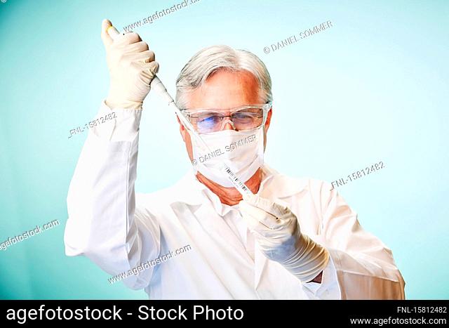 Grey-haired laboratory assistant with pipette fills Corona sample into test tube