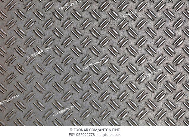 Dark gray industrial anti slip embossed metal steel plate with double diagonal bumps of diamond pattern texture, background, close up