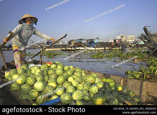Woman in conical hat rows boat of water melons Cai Ran floating market near Can Tho Vietnam
