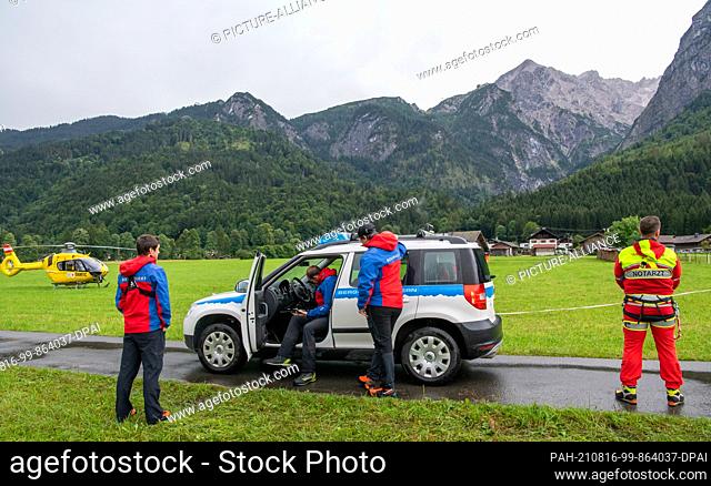 16 August 2021, Bavaria, Grainau: Mountain guards and an emergency doctor are ready for deployment by helicopter after a flood wave in the Höllentalklamm (l)