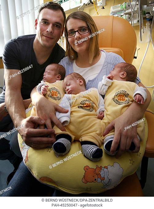 The triplets (L-R) Till, Max and Ben lie in the arms of their parents Thomas and Marie Osswald in the South City Hospital in Rostock, Germany, 03 January 2014