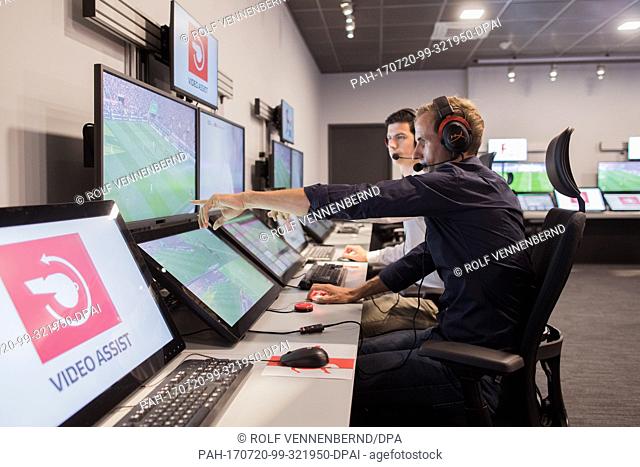 Referee Sascha Stegemann (L) and an operator sit in front of screens showing match sequences in a video assistant referee centre in Cologne, Â Germany