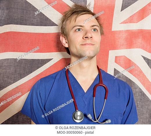 Confident male surgeon looking up with British Flag in background