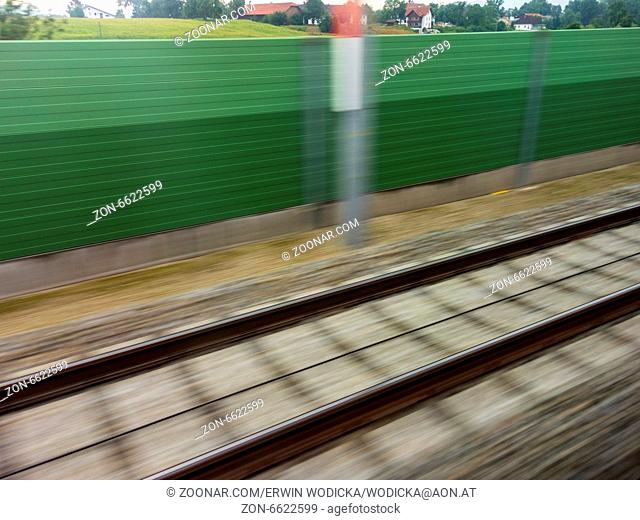 Gleise und Schienen in Bewegung aus einem fahrenden Zug heraus. Symbolfoto für Zugfahrt, Tempo und Dynamik