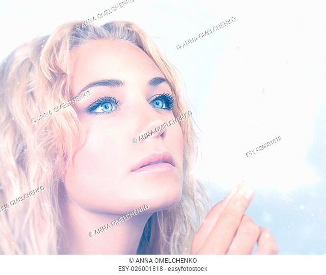Closeup portrait of beautiful blond woman holding in hand magical glowing snowflakes, with wonder looking on Christmas miracle
