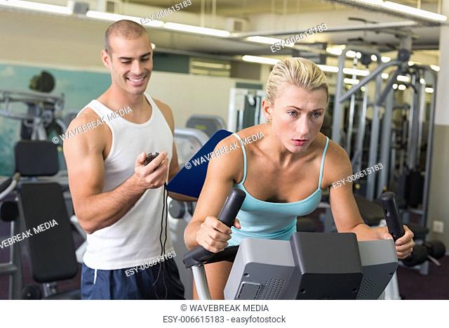 Trainer timing his client on exercise bike at gym