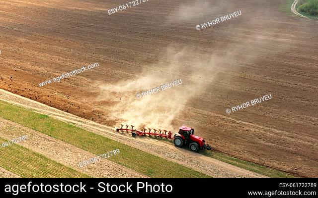 4K Aerial Flat View Tractor Plowing Field In Spring Season. Beginning Of Agricultural Spring Season. Cultivator Pulled By A Tractor In Countryside Rural Field...
