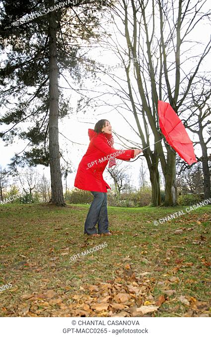 YOUNG WOMAN TRYING TO CLOSE HER UMBRELLA TURNED INSIDE OUT BY THE WIND