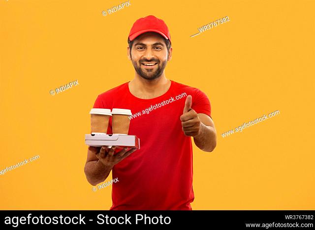 A HAPPY DELIVERY GUY STANDING WITH PACKED FOOD