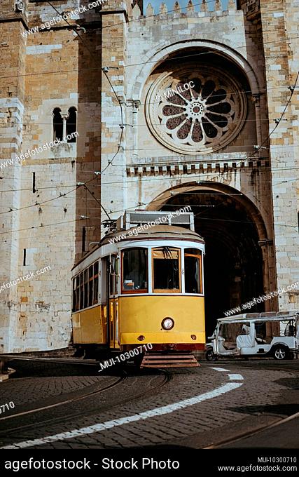 Quaint yellow tram passes directly in front of the Se Cathedral in Lisbon, Lisboa, Lissabon, Portugal, Europe