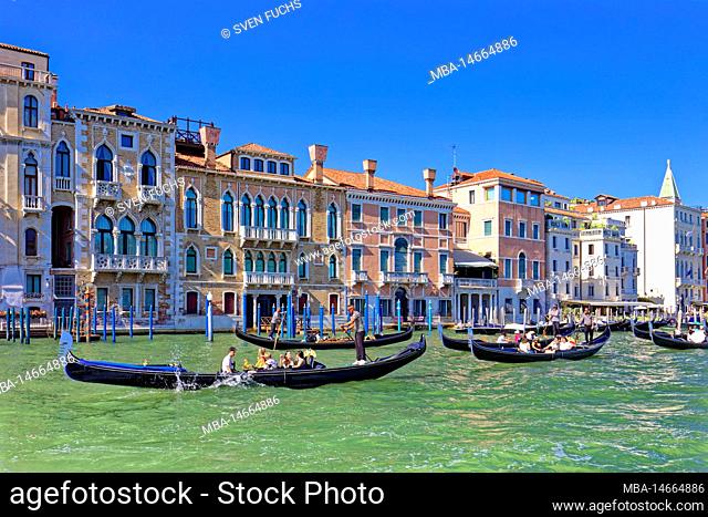 Gondolas take tourists past houses on the Grand Canal in Venice