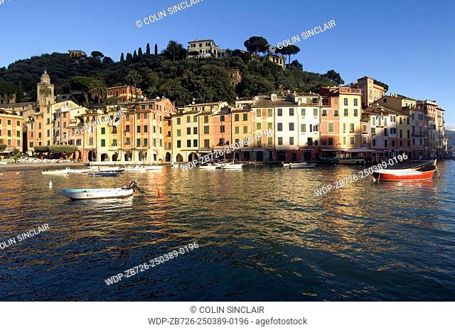 Portofino, Ligurian Coast, Italy, Port, Boats, Colourful homes, Reflections in Sea, Backdrop hillsides with pines and beautiful houses, Horizontal, Blue sky