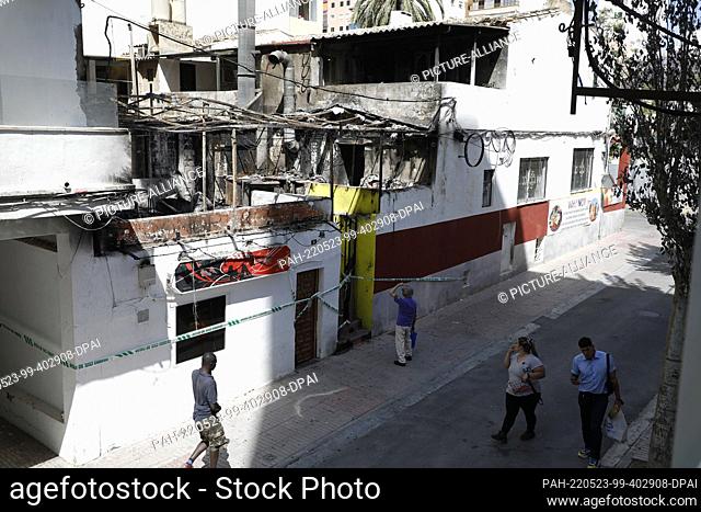23 May 2022, Spain, Palma: People walk past the restaurant ""Why Not Mallorca?"" after a fire. Police have arrested 13 German holidaymakers on Mallorca for...
