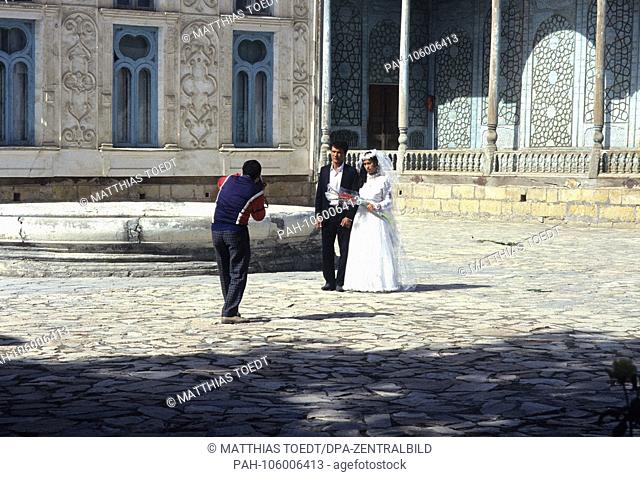 An Uzbek wedding couple settles in the courtyard of the palace of Sitorai Mohi Xosa, the summer residence of the last emir, photographed