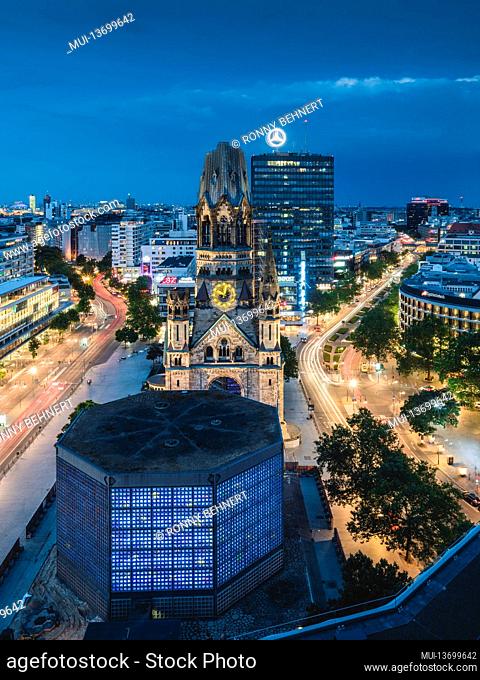 Illuminated Memorial Church on Breitscheidplatz in Berlin with a view of the Europa Center in the evening