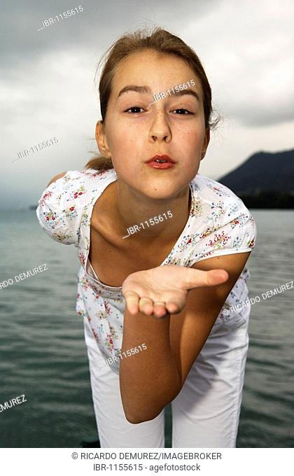 Young girl at a lake, blowing a kiss