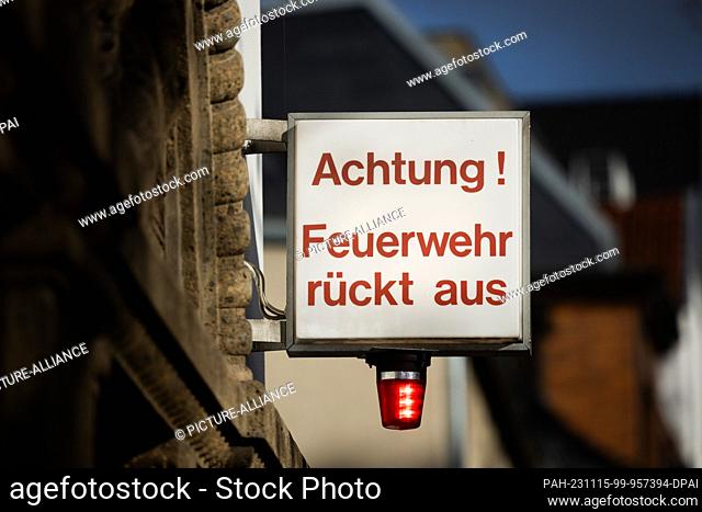 15 November 2023, North Rhine-Westphalia, Cologne: ""Attention! Fire department moving out"" and a light shine at a fire station to indicate an imminent...