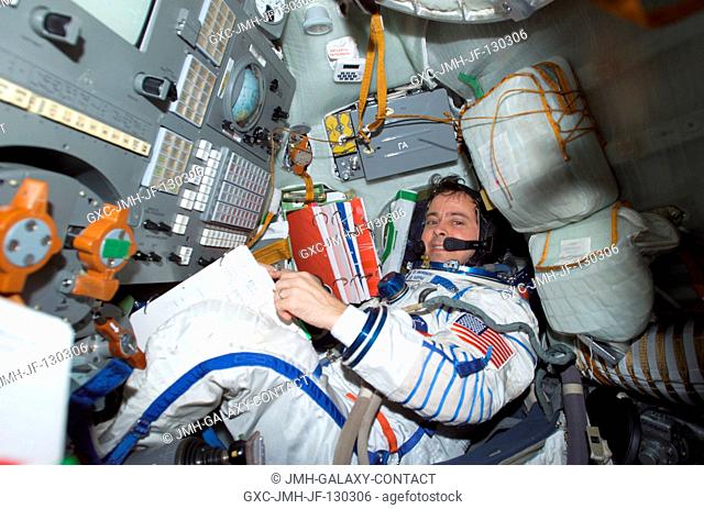 Astronaut Daniel W. Bursch, Expedition Four flight engineer, wearing a Russian Sokol suit, is seated in the Soyuz 3 spacecraft that is docked to the...