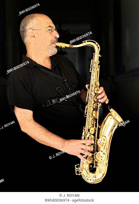 saxophone player dressen in black in front of a black background