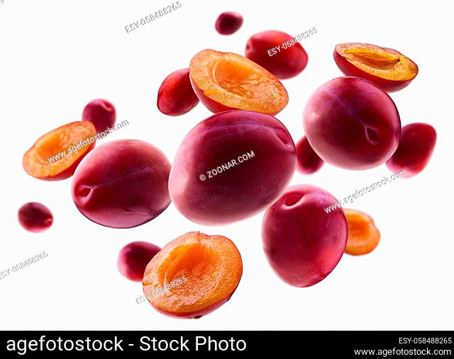 Red plums levitate on a white background