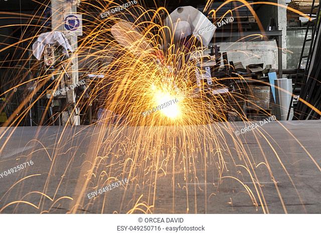 Worker Grinding metal in a workshop with sparks flying